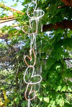 a wind chime hanging from the side of a tree in a garden with lots of green leaves