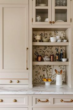 a kitchen with white cabinets and marble counter tops, gold pulls on the cupboards