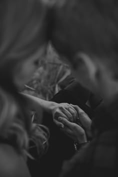 black and white photograph of two people holding hands with each other on a couch in the living room