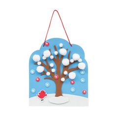 a wooden sign with a tree and snow on the branches, hanging from a red string