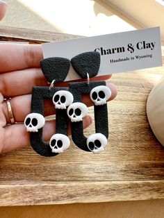 a pair of skully earrings is being held up by someone's hand on a wooden table