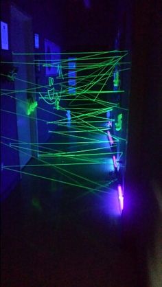 a room filled with green and purple lasers on the wall next to a doorway