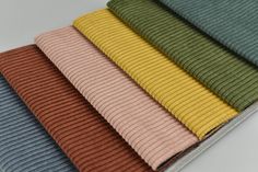 several colors of ribbed fabric on a white surface