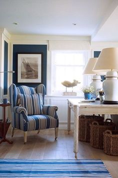 a blue and white striped chair sitting in a living room next to a table with baskets on it