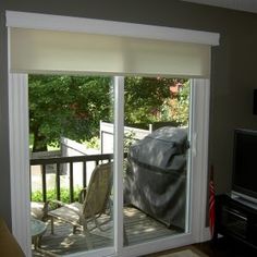 a living room with sliding glass doors leading to a deck and outdoor furniture in the background