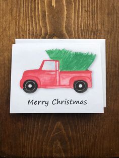 a red truck with a green christmas tree on it's back is sitting on a wooden surface