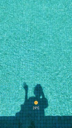 the shadow of a person standing next to a swimming pool