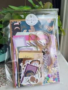 an assortment of cards and papers in a plastic bag on a table next to a potted plant