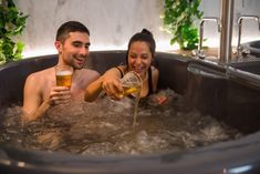 two people in a bathtub drinking beer