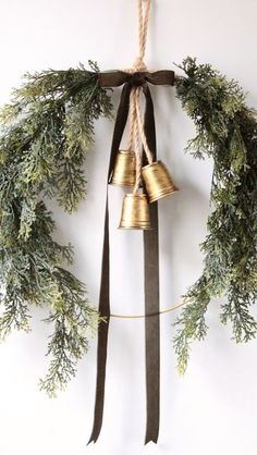 a christmas wreath with bells hanging from it's side and tied to the wall