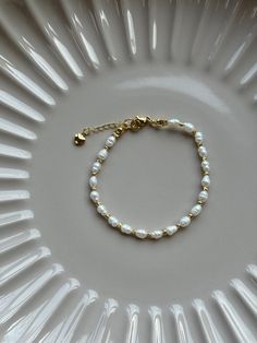 Minimalistic 18k gold plated freshwater pearl bracelet with 18k gold plated beads. It forms a gorgeous base in your jewellery collection and goes nicely with any outfits. Adjustable. Please note pearls are organic and shape and colour may vary. DETAILS: - Material:  Freshwater pears 3,4mm/18k gold plated beads and a closure - Bracelet length: 18cm with an extension chain 21cm overall - Hypoallergenic  -Nickel free - Recycled - Tarnish resistant MATERIAL AND CARE: - Our beautiful pieces are made out of high quality 18k gold plated stainless steel  material which holds up to the elements of daily life.   - To extend the life of the jewellery we highly advise to: ~ wipe clean with a polishing cloth after wearing to keep it clean and shiny ~ store in a cool dry place ideally in our soft pouch. Minimalistic Bracelet, Small Bead Bracelet, Handmade Jewlery, Bracelet Dainty, Dainty Bracelet, Gold Bead Bracelets, Freshwater Pearl Bracelet, Minimalist Bracelet, Dainty Bracelets