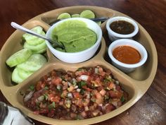 a plate filled with lots of different types of food next to dipping sauces and pickles