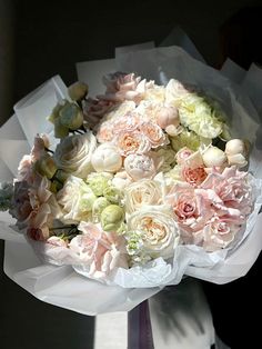 a bouquet of white and pink flowers is held by someone