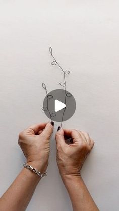 two hands are holding a piece of metal wire