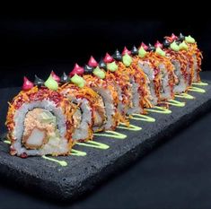 sushi rolls are arranged on a black platter