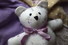 a white teddy bear sitting on top of a purple blanket