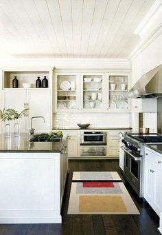 a kitchen with white cabinets and black counter tops is pictured in this image, there are dishes on the shelves above the stove