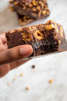 a hand holding a piece of chocolate peanut butter brownie