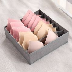 several pieces of pink and white cake in a gray box on a white blanket with a window behind it