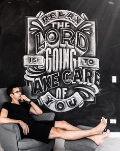 a man sitting on a chair in front of a chalkboard with words written on it