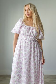 Expertly crafted for style and comfort, our Blossom Floral Print Midi Dress in Lavender is perfect for any occasion. Featuring charming puff sleeves, a flattering elastic waist, and convenient pockets, this dress effortlessly combines classic elegance with modern functionality. The square neck adds a touch of sophistication, making it a must-have for any wardrobe. square neckline puff sleeves elastic waist lined 100% polyester true to size model is wearing a medium Short Sleeve Dresses With Gathered Waist For Garden Party, Spring Purple Puff Sleeve Dresses, Feminine Purple Puff Sleeve Mini Dress, Feminine Mini Dress With Gathered Waist, Feminine Lavender Floral Print Midi Dress, Lavender Dresses With Smocked Back For Spring, Lavender Dress With Smocked Back For Spring, Purple Midi Dress With Smocked Bodice, Feminine Lavender Midi Dress With Floral Print