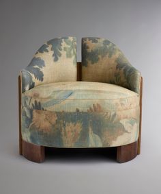 an upholstered chair with floral fabric and wooden legs, on a gray background