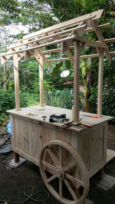 an outdoor bar made out of wood with wheels on the ground and trees in the background