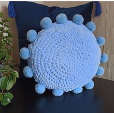 a blue pillow sitting on top of a black table next to a potted plant