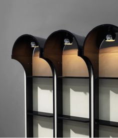 three black bookshelves with lights on each shelf