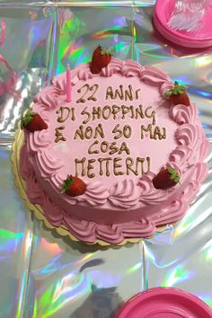 a pink birthday cake sitting on top of a table