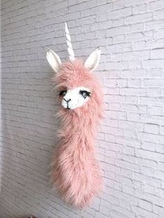 a pink llama head hanging on a white brick wall