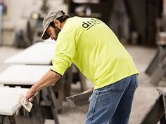 a man in a yellow shirt is sanding up some benches