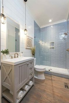 a bathroom with blue tile walls and wood flooring, along with a white toilet