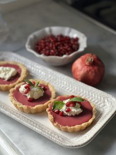 three small tarts on a white tray with pomegranates