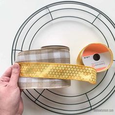 a person is holding two rolls of tape on a wire rack with a circular object in the background