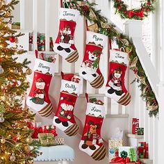 christmas stockings hanging on the wall next to a staircase decorated with holiday decorations and presents