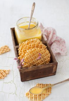 some waffles are sitting in a wooden box next to a jar of honey