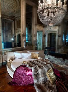 a luxurious bedroom with chandelier, bed and couch in the middle of it