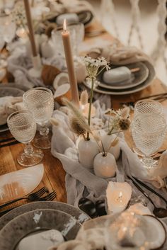 the table is set with plates, silverware and white flowers in vases on it