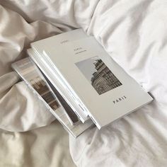 an open book sitting on top of a bed covered in white sheets and blankets,