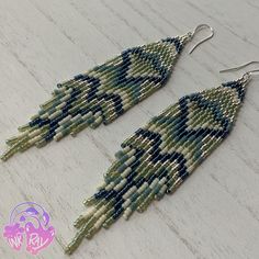 two pairs of beaded earrings with green and white beads hanging from them on a wooden surface