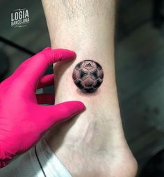 a woman's foot with a soccer ball tattoo on her left ankle and pink gloves