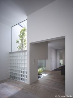 an empty room with wood floors and white walls, looking out onto the garden area