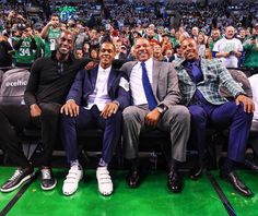 three men sitting next to each other in front of an audience at a basketball game