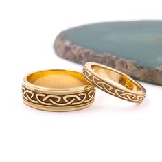 two gold wedding rings sitting next to each other