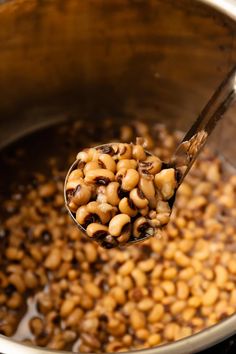 a ladle full of beans is being held over the pot