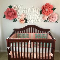 a baby crib with pink and orange flowers on the wall next to it's name