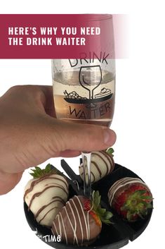 a hand holding a glass filled with strawberries and chocolate covered strawberries on a plate