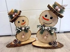 two snowmen made out of wood sitting on top of a wooden floor next to each other