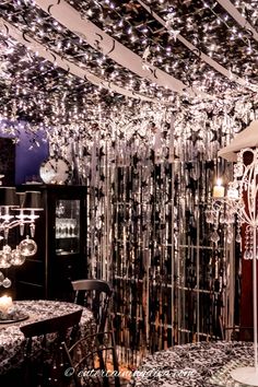 a dining room with chandeliers hanging from the ceiling and tables in front of it